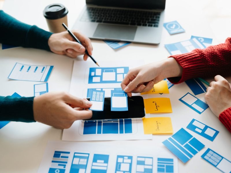 Close up view of UI developer team brainstorming on their project with laptop, smartphone and digital tablet. Creative digital development agency.